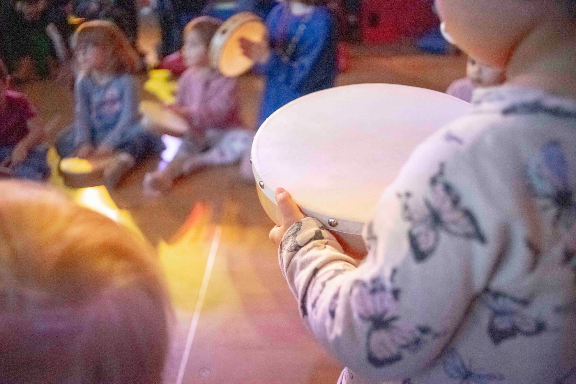 Kinder sitzen im Kreis und spielen gemeinsam auf Rahmentrommeln
