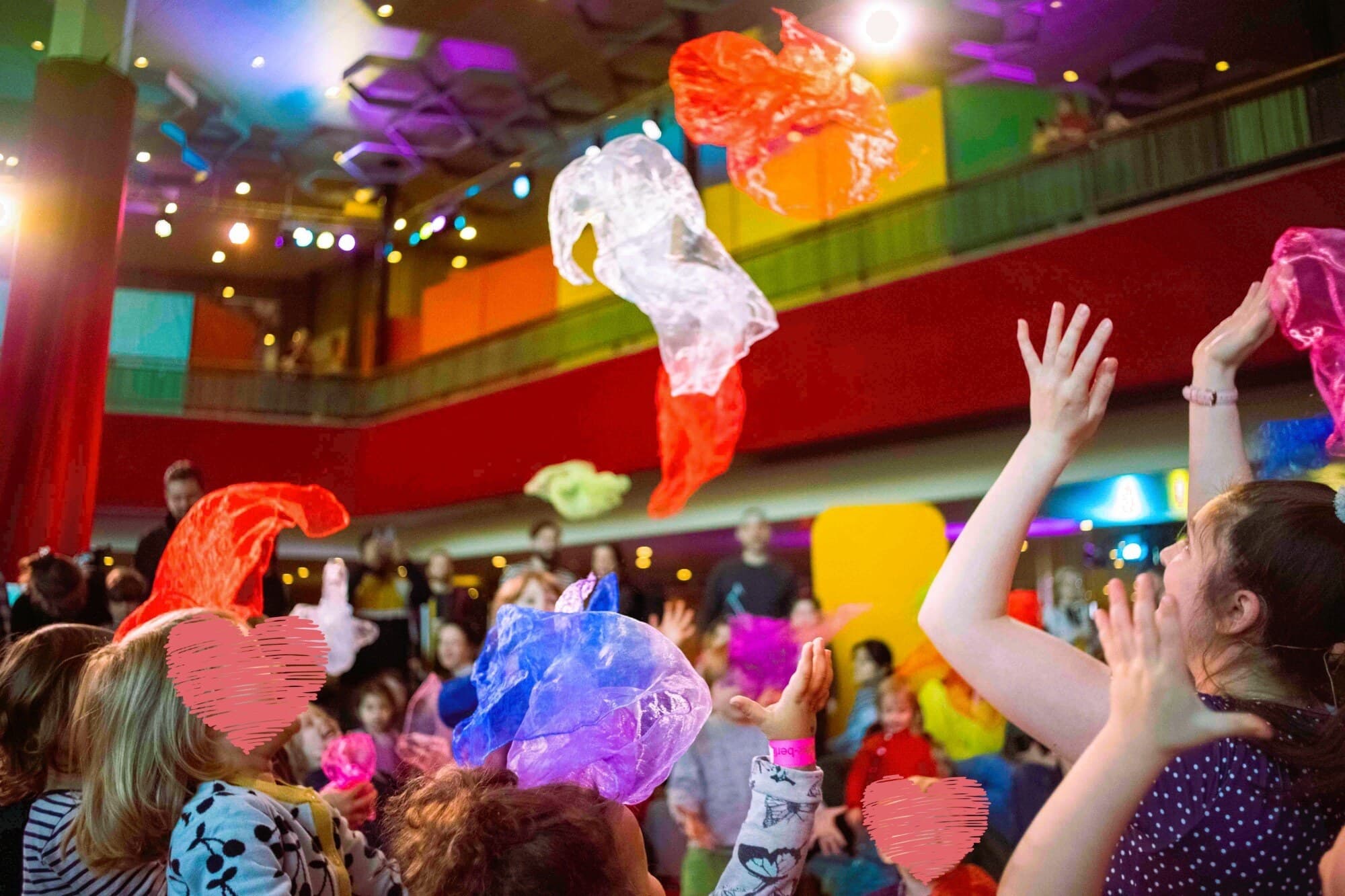 Mitmachkonzert im FEZ Berlin: Kinder und Eltern werfen bunte Chiffontücher in die Luft
