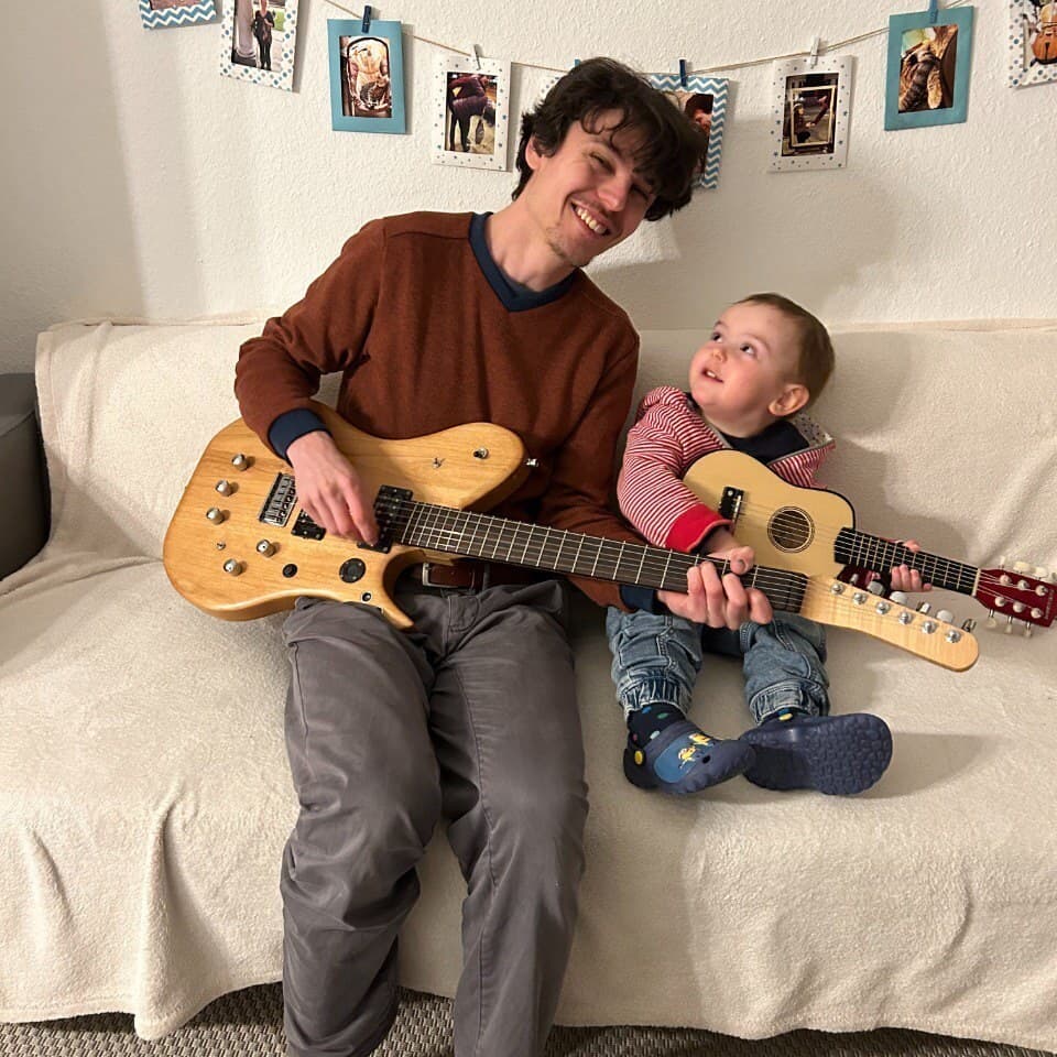 João Neves spielt gemeinsam mit seinem kleinen Sohn Gitarre auf dem Sofa