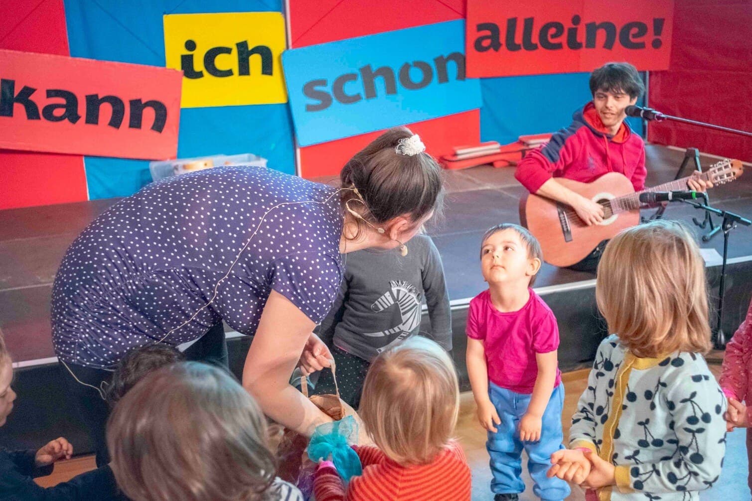 Kinderkonzert „Kann ich schon alleine!“: Magdalena verteilt Tücher an die Kinder, João begleitet auf der Gitarre